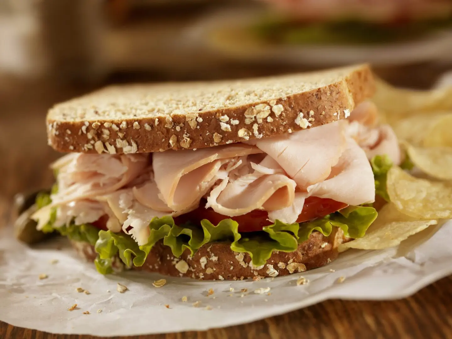 Turkey sandwich with lettuce, tomato, and chips