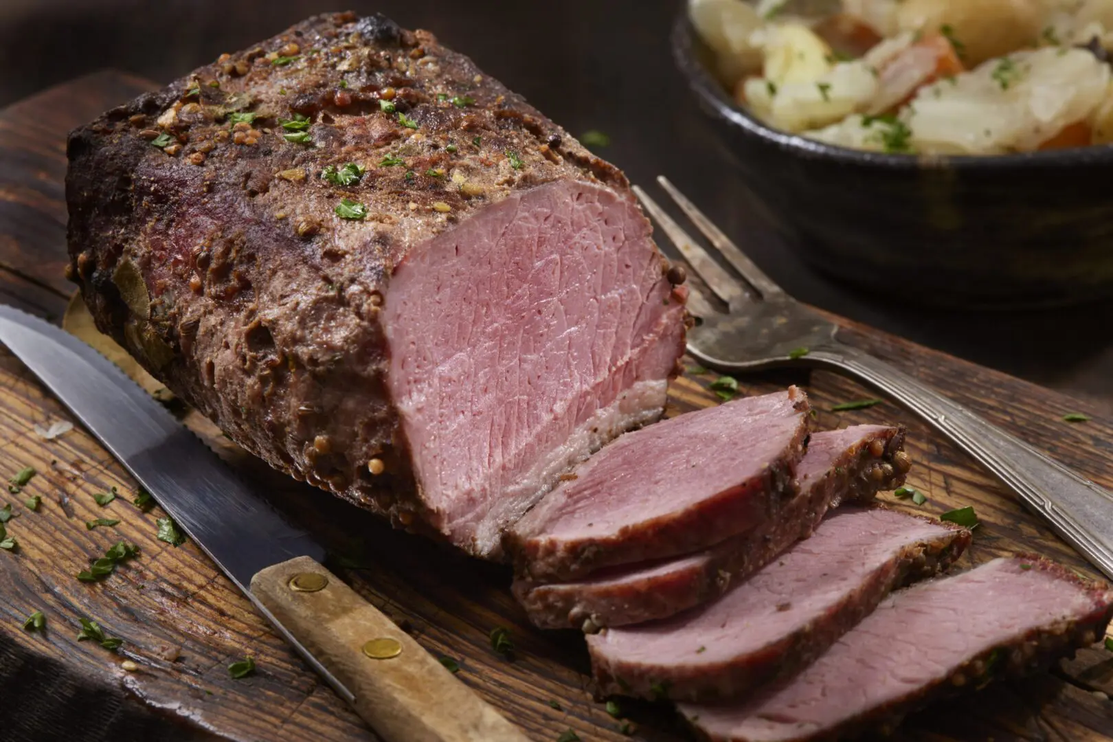 Sliced roast beef on wooden cutting board