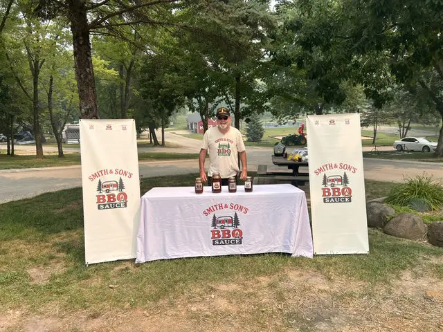 Man promoting BBQ sauce at outdoor event.