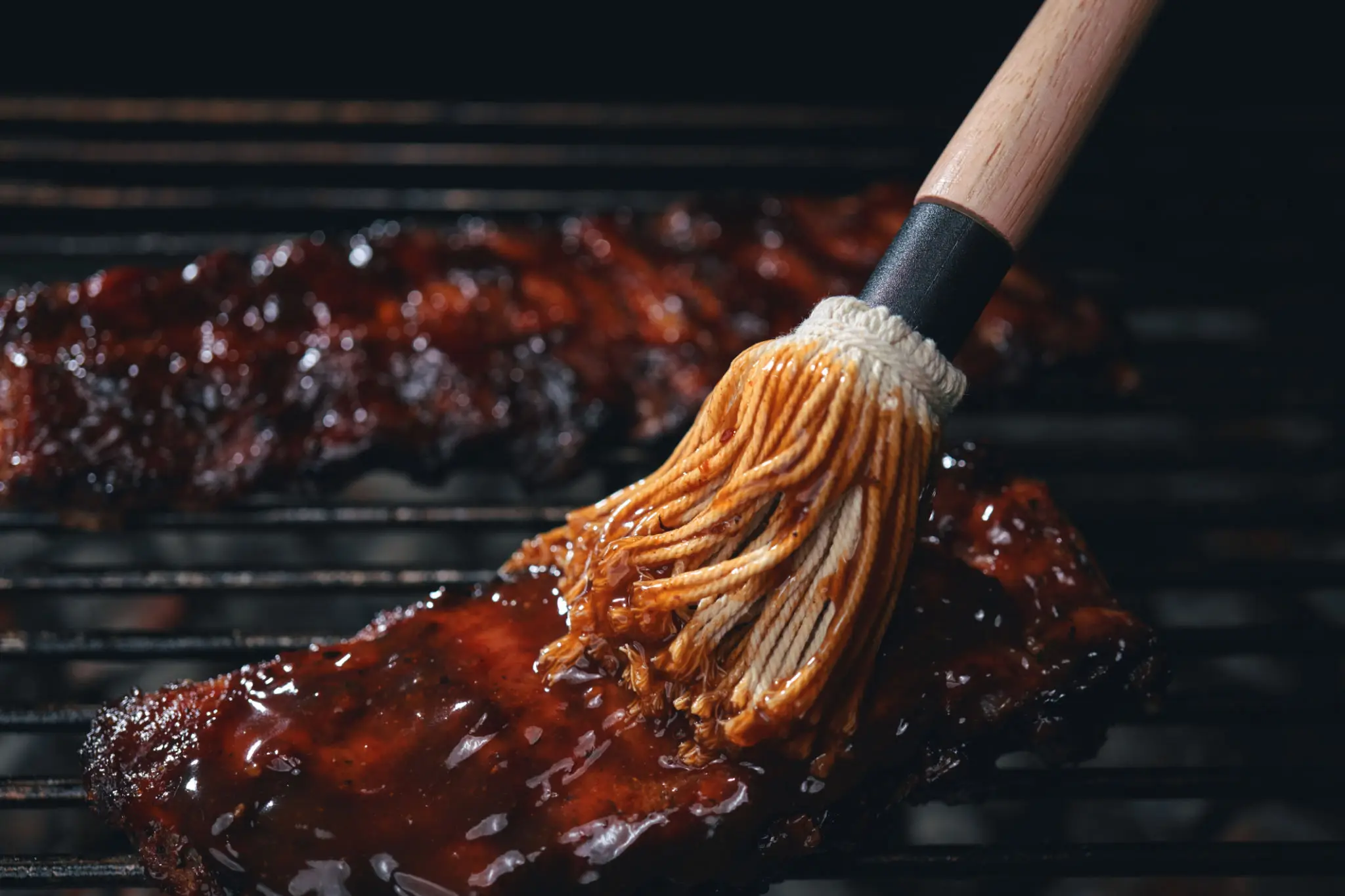 Juicy ribs on grill with basting brush
