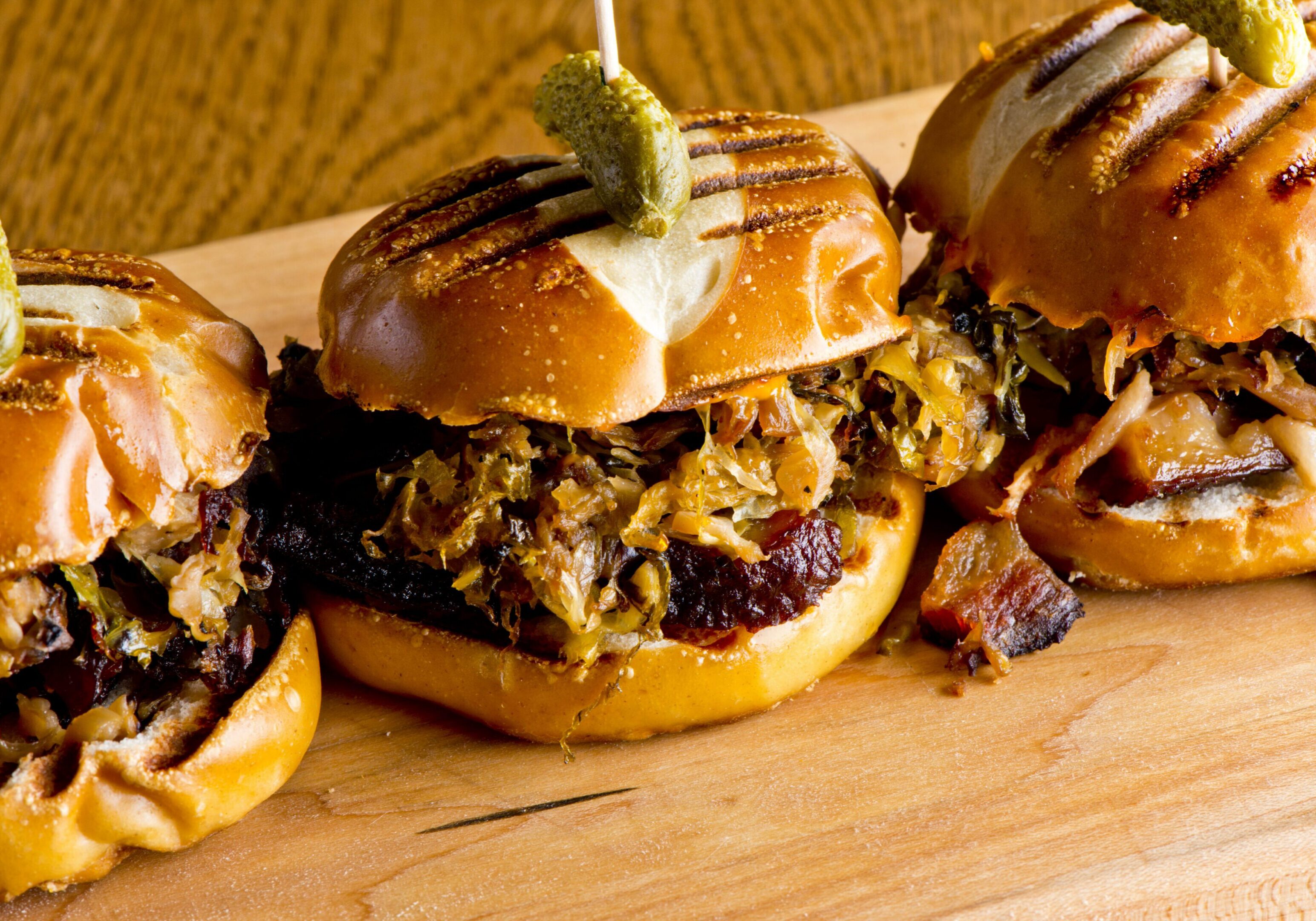Three grilled BBQ sliders with pickles and onions