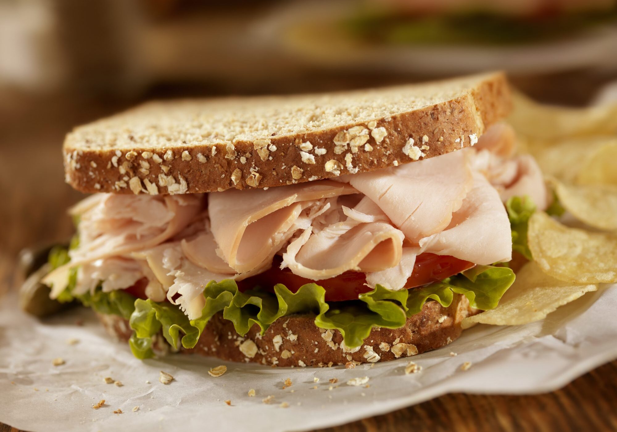 Turkey sandwich with lettuce, tomato, and chips