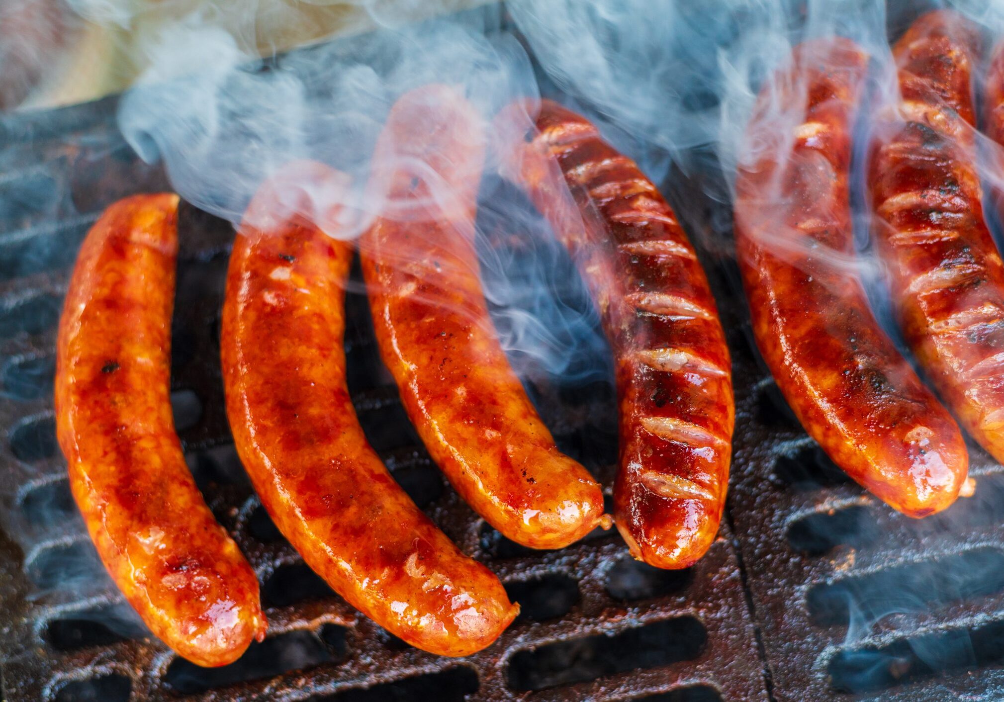 Smoky grilled sausages sizzling on barbecue